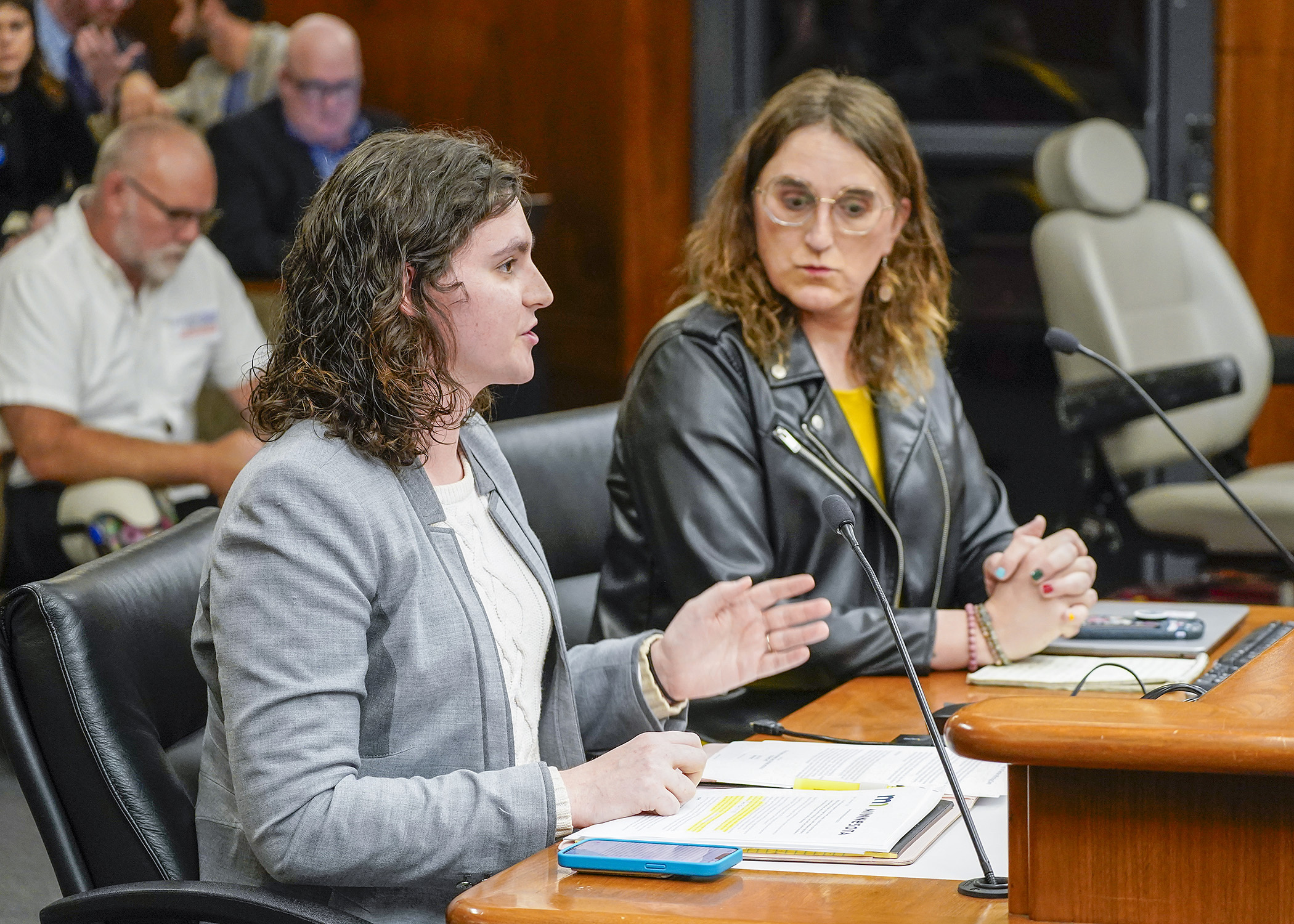 Ash Tifa, legal services program coordinator at Rainbow Health, testifies in support of a bill sponsored by Rep. Leigh Finke, right, that would require health plan coverage of gender-affirming care. (Photo by Andrew VonBank) 